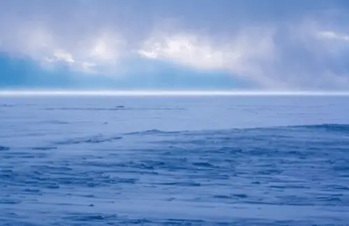 Photo of snowstorm approaching over frozen lake