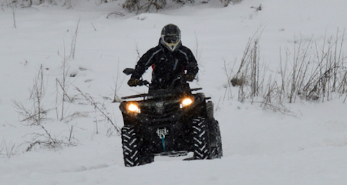 Photo of man driving ATV in snowy landscape