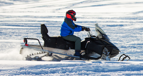 Photo of person driving snowmobile on frozen lake