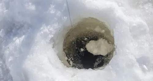 Photo of ice fishing hole with line from rattle reel