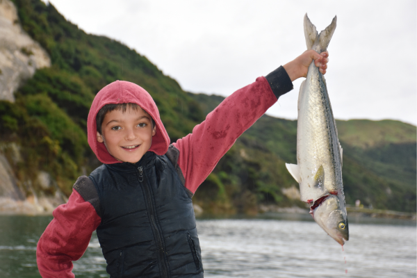 Boy proudly holding up a fish he just caught