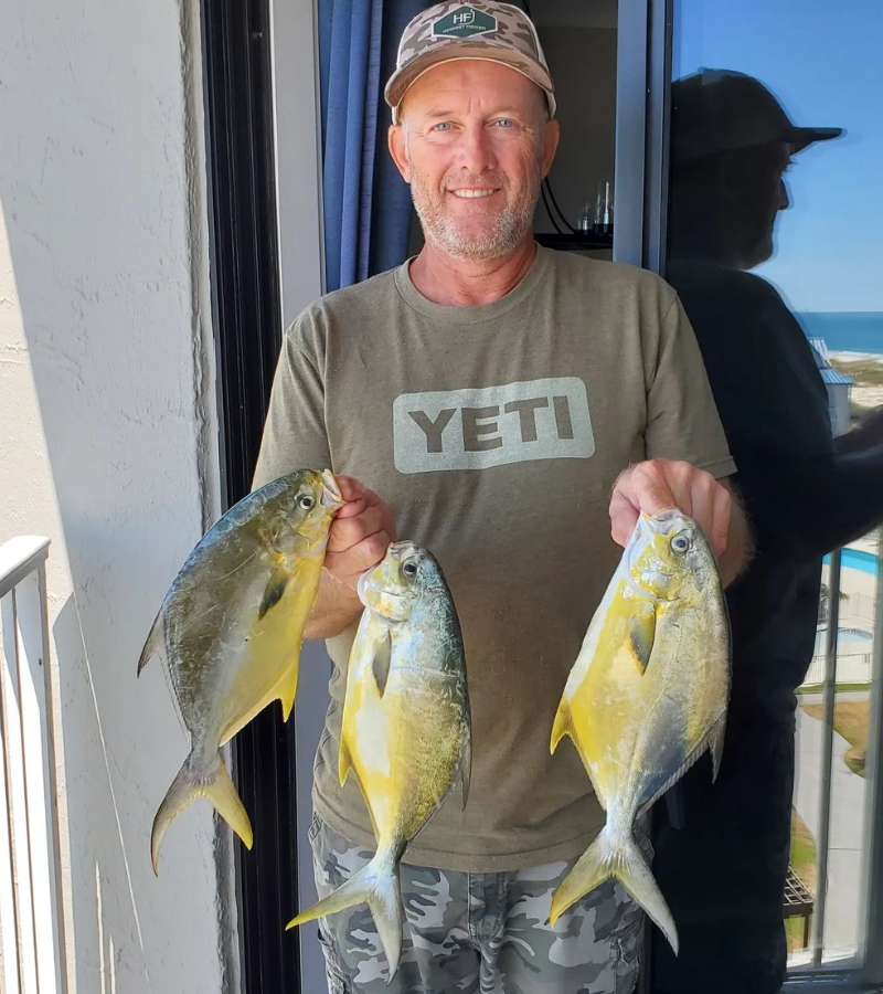 Photo of angler holding 3 pompano fish caught while surf fishing with a pompano rig