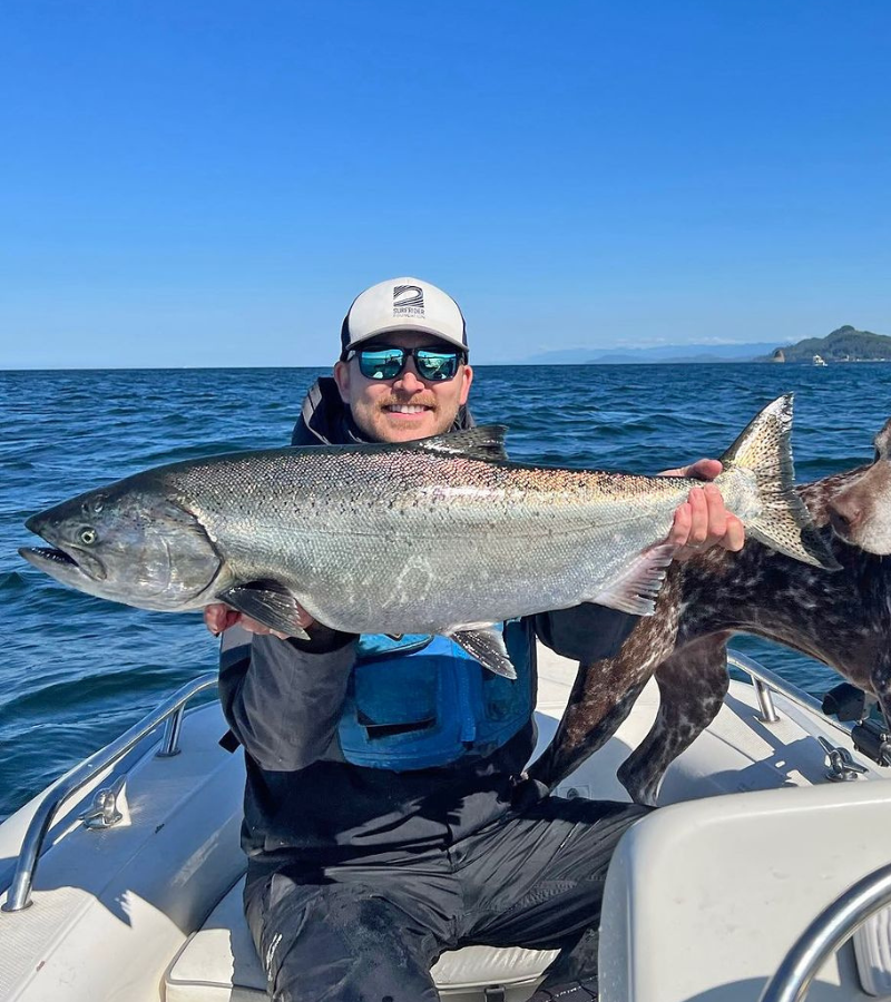 Angler on a boat holding a large king salmon caught with a mooching rig