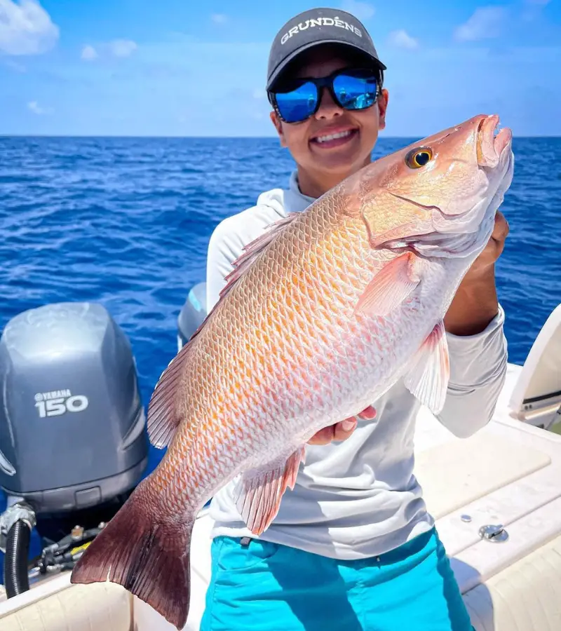 Photo of an angler on a boat holding a large mutton snapper caught while deep sea fishing with a dropper loop rig